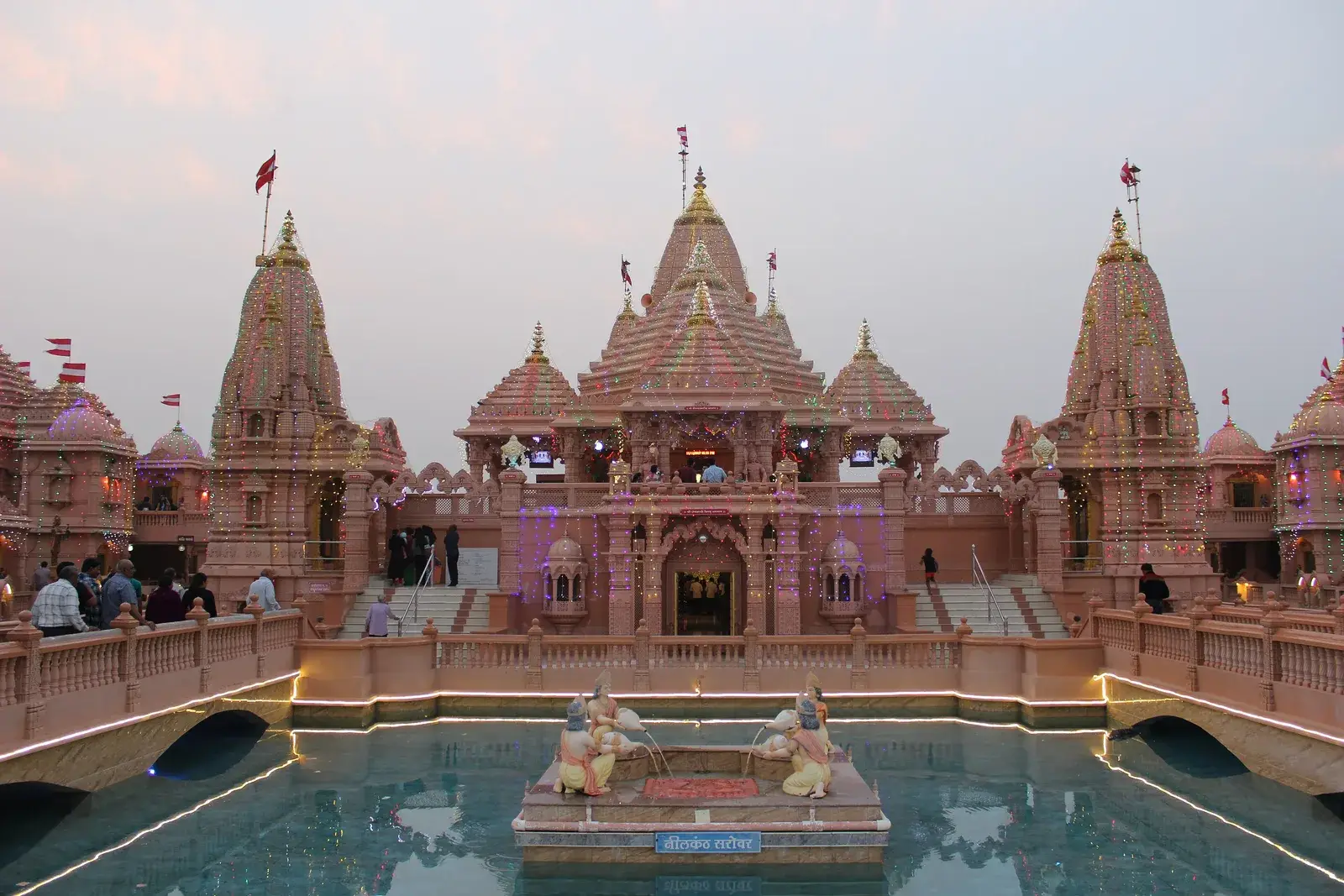 The spires of Nilkanth Dham, Poicha, across the temple lake at dusk