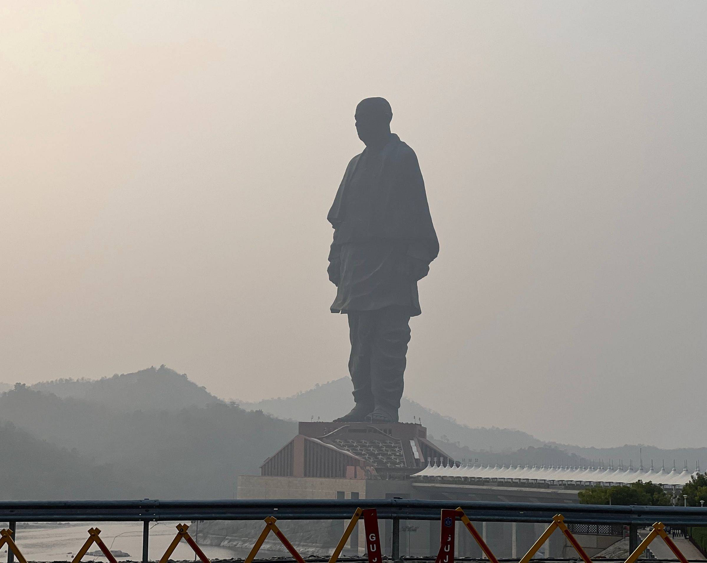 The Statue of Unity in silhouette against a hazy dusk sky